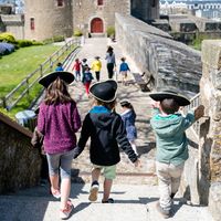 Enfants de dos portant un tricorne sur les remparts du château