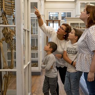 Famille et guide face à une vitrine présentant un squelette 