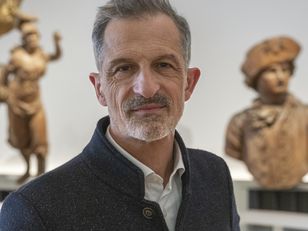 Portrait du directeur dans une salle d'exposition permanente du musée, entouré de sculptures maritimes anciennes – photo prise au Musée national de la Marine.