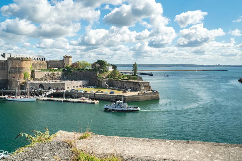 Vue sur le château de Brest, siège du musée national de la Marine, en bord de mer sous un ciel dégagé.