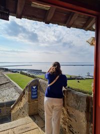 Vue panoramique sur la rade de Brest depuis le château de Brest, avec une visiteuse admirant le paysage maritime depuis les remparts du musée national de la Marine.