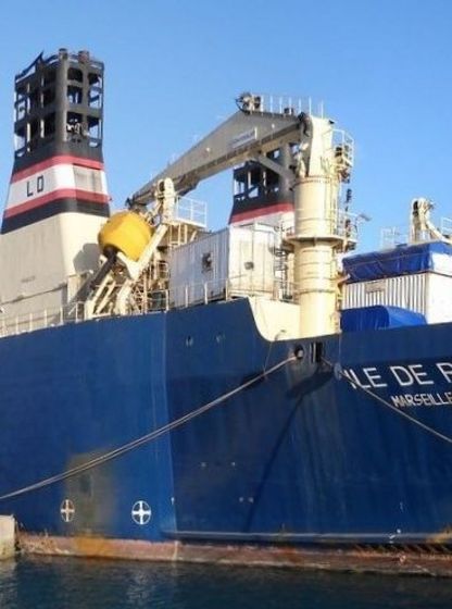 Navire câblier amarré au port, équipé de grues et de treuils pour la pose et la réparation de câbles sous-marins de télécommunication.