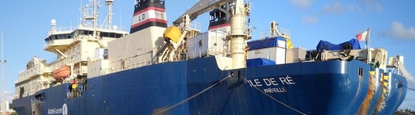 Navire câblier amarré au port, équipé de grues et de treuils pour la pose et la réparation de câbles sous-marins de télécommunication.