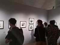 Groupe de visiteurs contemplant des photographies encadrées en noir et blanc dans une salle d’exposition du musée.