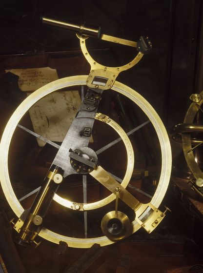 Instrument de navigation ancien en laiton, de type cercle de réflexion, composé d’un grand anneau gradué avec lunettes de visée et mécanismes de réglage, présenté dans un coffret en bois.