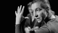 Portrait en noir et blanc de la conteuse Sandrine Gniady en pleine interprétation, main levée et regard expressif, lors de son spectacle Le sable de la mer.