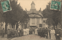 "Carte postale ancienne en noir et blanc montrant l’intérieur de l’Hôpital Maritime de Rochefort-sur-Mer : deux rangées de personnels (militaires en uniforme, infirmiers et aides-soignants en blouse et coiffe blanche) encadrent une allée centrale bordée d’arbres. En arrière-plan, la façade symétrique de l’hôpital, dotée d’un pavillon central à toit mansardé, de lucarnes et d’une horloge sculptée dans le fronton, ainsi qu’un auvent à l’entrée. Deux timbres-poste verts de 5 c. figurent dans les coins supérieurs, et en bas, en lettres rouges, la légende « V.G. 19. ROCHEFORT-sur-MER – Intérieur de l’Hôpital de la Marine »."