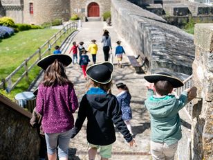 Enfants de dos portant un tricorne sur les remparts du château