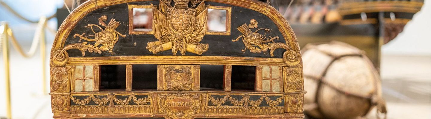 Modèle de poupe d’un vaisseau orné de dorures et sculptures marines exposé au musée national de la Marine à Paris.