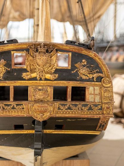Modèle de poupe d’un vaisseau orné de dorures et sculptures marines exposé au musée national de la Marine à Paris.