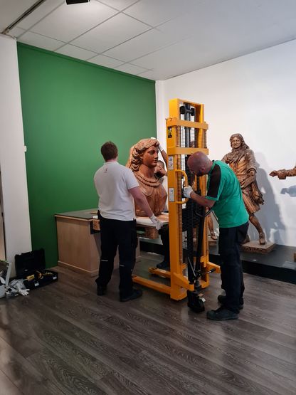 Deux prestataires manipulent la figure de proue La Sibylle à l’aide d’un engin de levage, lors de sa mise en place au musée de Toulon