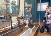 Une mère et son fils observent des maquettes de navires anciens dans une vitrine du musée national de la Marine de Rochefort.