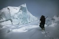 Paysage de glace en Arctique, 2012 – photographie de Jean Gaumy (Magnum Photos) montrant un explorateur face à un immense bloc de glace dans une étendue enneigée.