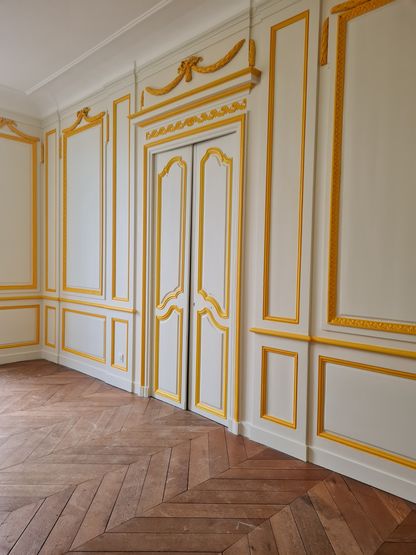 Salle vide restaurée avec boiseries blanches et moulures dorées dans le musée national de la Marine à Rochefort.