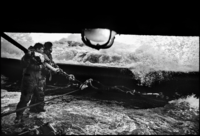 Photo de deux marins face à une vague