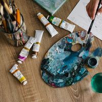 Palette de peinture bleue avec pinceaux et tubes de peinture colorés posés sur une toile de jute, matériel d’atelier artistique pour un cycle de peinture au musée national de la Marine