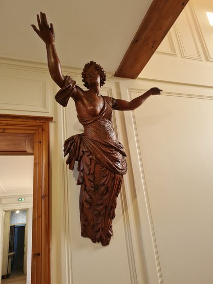 Figure de proue suspendue au plafond dans un espace intérieur repensé du musée national de la Marine à Rochefort.