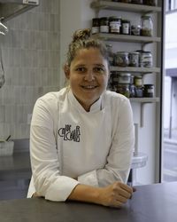 Portrait de la cheffe Chloé Charles dans sa cuisine, en tenue professionnelle, invitée d’une conférence au Musée national de la Marine.