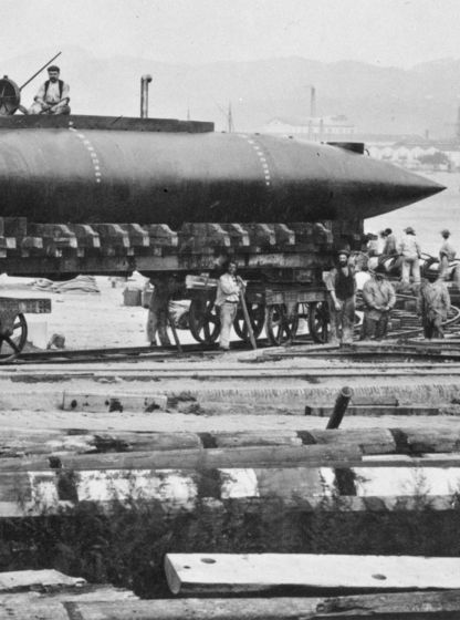 Essais du sous-marin Gymnote en 1888, prototype posé sur un quai avec équipage et grue en arrière-plan, photographie en noir et blanc.