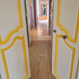 Vue en perspective d’une enfilade de salles réaménagées avec portes blanches et moulures dorées au musée national de la Marine à Rochefort.