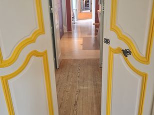 Vue en perspective d’une enfilade de salles réaménagées avec portes blanches et moulures dorées au musée national de la Marine à Rochefort.