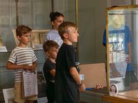 Groupe d’enfants participant à une activité ludique avec un quiz au musée national de la Marine, observant attentivement une vitrine.