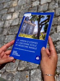 Personne tenant un livret de visite facile à lire et à comprendre (FALC) dédié au jardin d’utopies, conçu pour l’accessibilité des publics