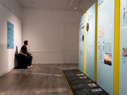 Espace repère avec dispositifs pédagogiques et panneaux explicatifs dans l’ancienne École de médecine navale de Rochefort, visiteur assis face aux contenus