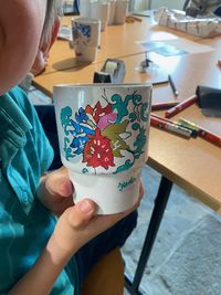 Enfant participant à un atelier créatif au musée de la Marine de Port-Louis, décorant un objet avec des motifs colorés inspirés de la mer.