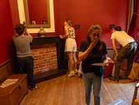 Participants à un escape game autour de Pierre Loti dans une salle de l'école de médecine navale, observant des indices près d’un meuble ancien.