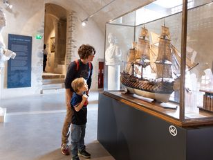 Enfant et sa mère face à la vitrine d'une maquette 