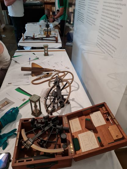 Instruments de navigation en cours d’examen et d’inventaire sur une table recouverte de tissu, lors d’une opération de conservation.