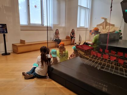 Enfants du Secours populaire écoutant des contes mythologiques au musée national de la Marine.