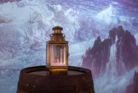 Lanterne en laiton posée sur un tonneau, éclairée devant une projection de vagues déchaînées – musée national de la Marine, Port-Louis.