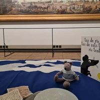 Espace de médiation pour enfants au musée : tapis bleu, peluche de marin et livre d’activités.
