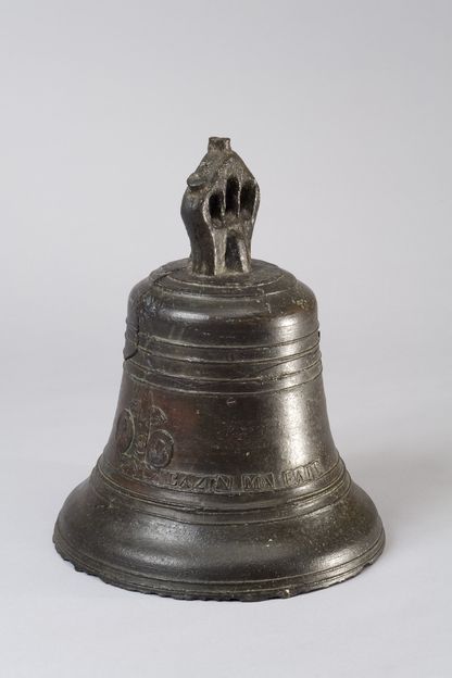 Cloche de bord en bronze patiné, posée sur un support de musée, avec une inscription gravée sur sa surface