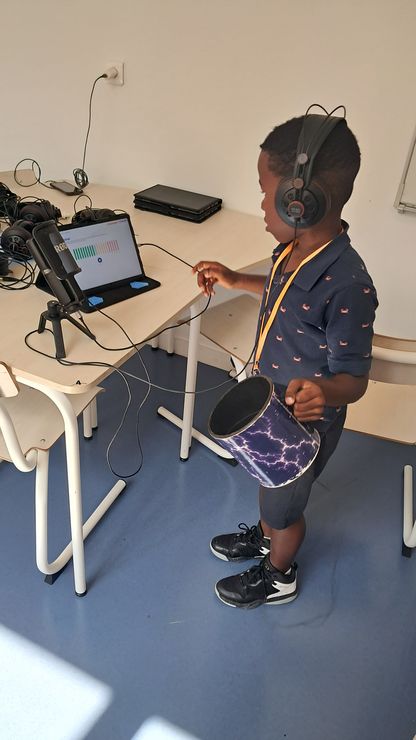 Atelier de création sonore – un enfant équipé d’un casque audio manipule une tablette numérique