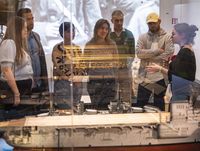 Vue d'une visite de groupe à travers une vitrine de maquettes