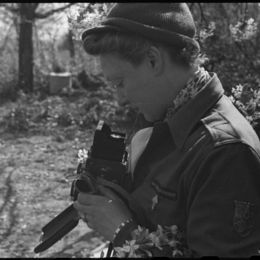 Portrait de Germaine Kanova, photographe du Service cinématographique de l’armée française (SCA), équipée d’un appareil Rolleiflex, debout en extérieur en Bade-Würtemberg (Allemagne), 11 avril 1945.