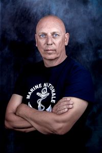 Portrait de Franck Seguin, photographe et nouveau Peintre officiel de la Marine, bras croisés, portant un tee-shirt « Marine nationale » à l'ancre.