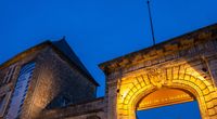 Façade illuminée du musée national de la Marine à Rochefort à la tombée de la nuit, avec son portail d'entrée en pierre.