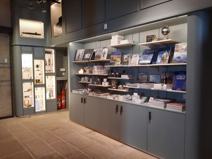Espace librairie de la boutique du musée national de la Marine de Brest, avec vitrines lumineuses d'objets décoratifs et étagères de livres.