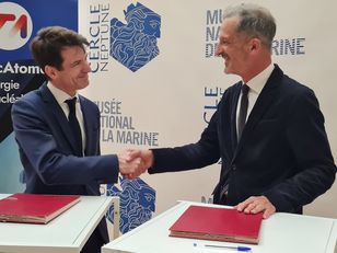 Signature d’un partenariat entre le musée national de la Marine et TechnicAtome, symbolisée par une poignée de main entre deux représentants en costume devant les logos de leurs institutions respectives.