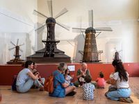 Animation pour les tout-petits au musée national de la Marine, dans la salle des maquettes de moulins, avec une médiatrice et des familles.