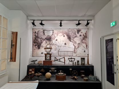 Vitrine d’exposition d’instruments de navigation anciens devant une grande carte du monde au musée national de la Marine à Toulon.