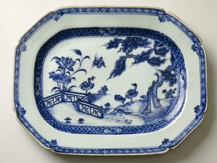 This porcelain plate is decorated with a riverscape featuring a tree and lotus flowers. Three ducks, depicted on the bank and in flight, complete the composition. 