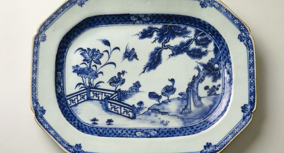 This porcelain plate is decorated with a riverscape featuring a tree and lotus flowers. Three ducks, depicted on the bank and in flight, complete the composition. 