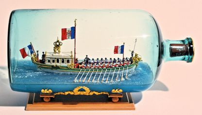 Maquette du canot impérial de Napoléon Ier réalisée dans une bouteille en verre, avec rameurs et pavillons français.