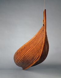 Reconstitution du bateau viking de Gokstad, navire sépulcral du IXe siècle : coque en bois sombre profilée en forme de feuille, aux bordés assemblés à clin et nervures apparentes. L’étrave haute et recourbée évoque la silhouette des langskip scandinaves, emblématiques de la tradition maritime viking.  