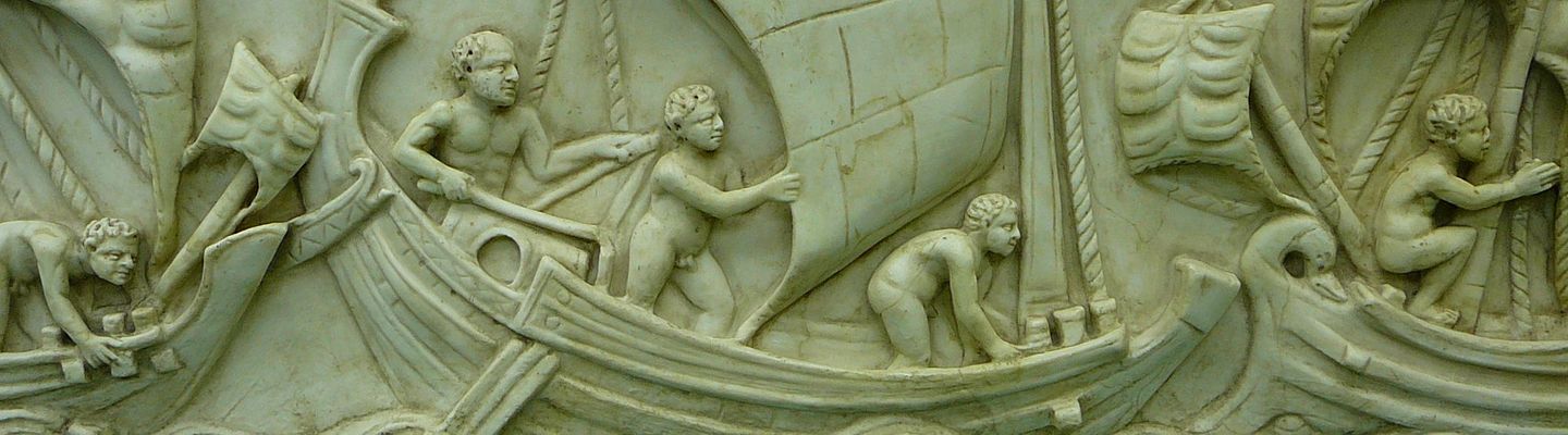 Bas-relief sculpté représentant une scène maritime avec des navires anciens affrontant les vagues, décor ornemental en pierre.